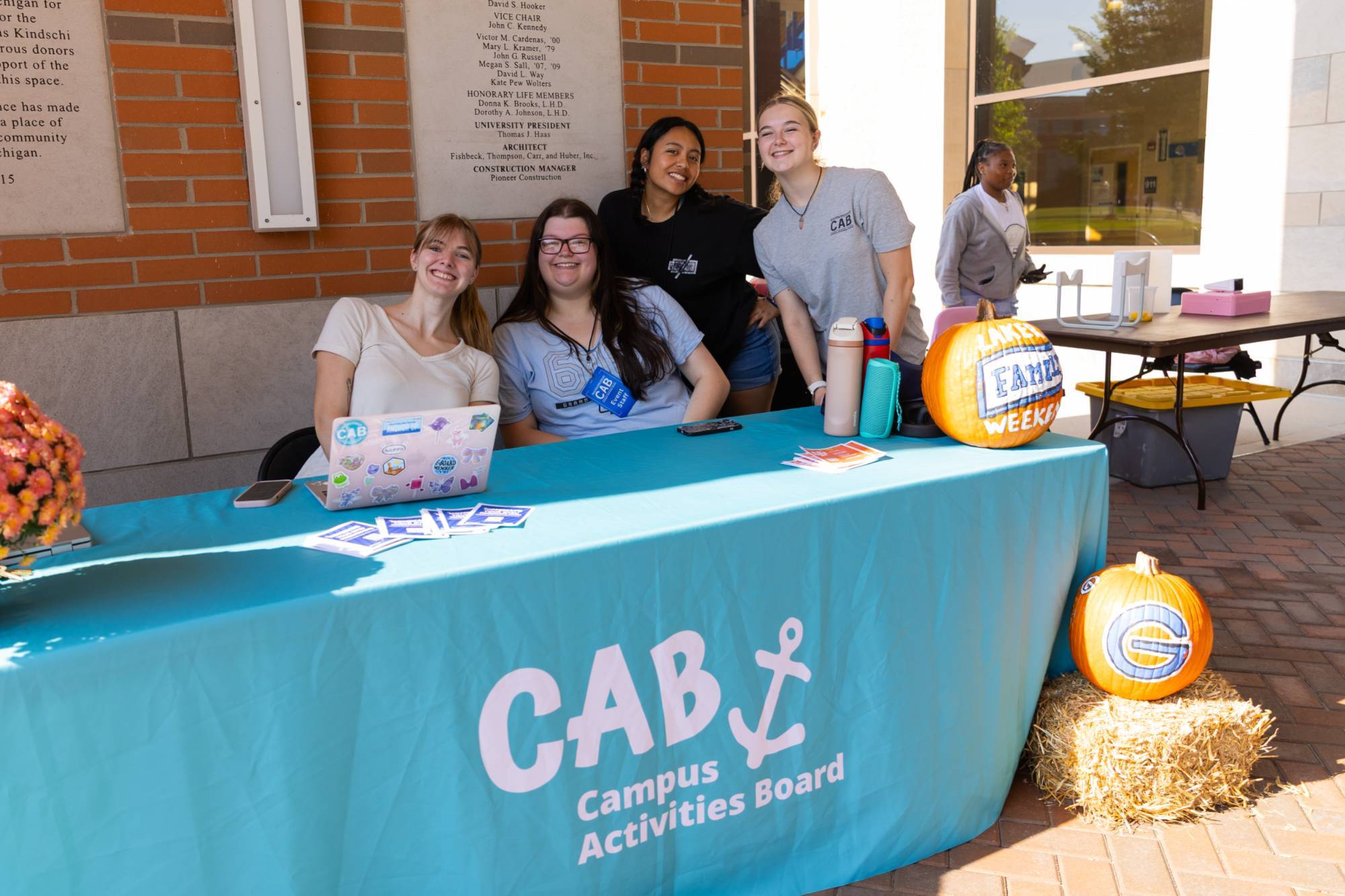 Students sitting behind a table covered in a teal table cloth that says "CAB Campus Activities Board"